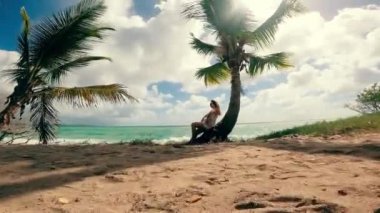 A woman is relaxing while sitting on a palm at the ocean shore