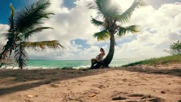 Жінка розслабляється, сидячи на долоні на березі океану — стокове відео