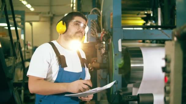 Hombre trabajador está observando el proceso de trabajo en una unidad de tipografía — Vídeos de Stock