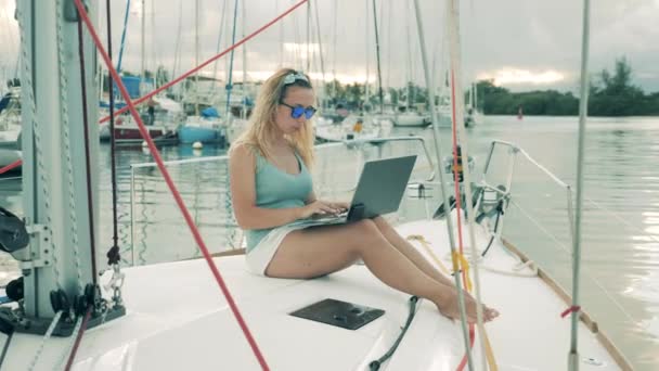 ヨットに座っている間、女性はラップトップで動作します. — ストック動画