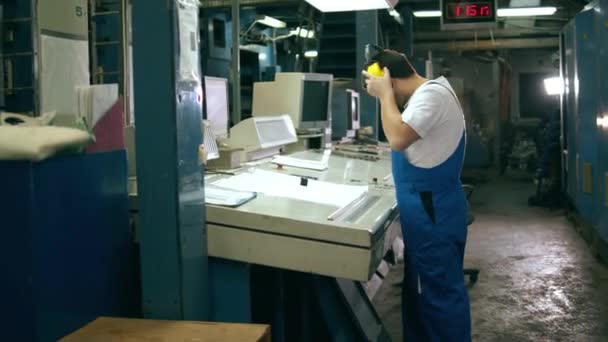 Ingeniero se pone auriculares y trabaja con un panel de control — Vídeo de stock