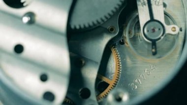 Metal dişliler saat mekanizmasının içinde hareket ediyor.