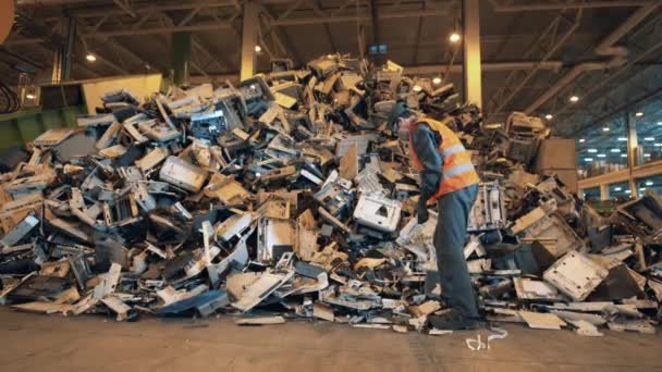 Muž pracovník uklízí pokoj s elektronickým odpadem. — Stock video