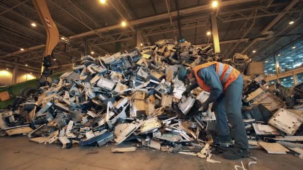 Trabajador de la fábrica de reciclaje clasifica la basura en una pila . — Vídeo de stock