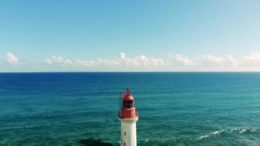 Üzerinde deniz feneri olan tropikal bir sahil.