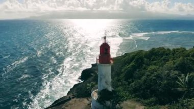 Beyaz bir deniz feneri olan güneşli bir sahil.