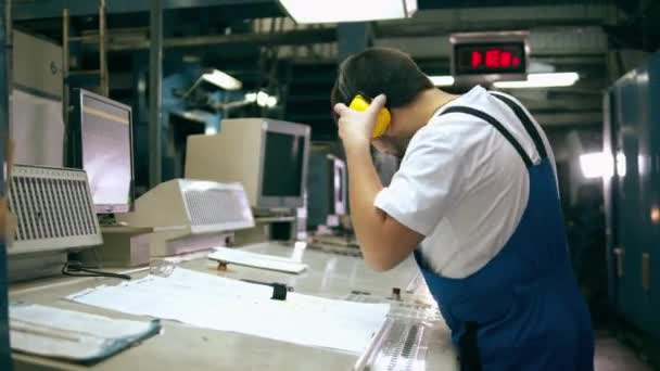 Trabalhador de tipografia coloca fones de ouvido e observa um layout — Vídeo de Stock