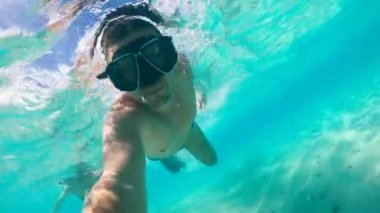 Bir adam okyanusa dalarken kendini filme alıyor.