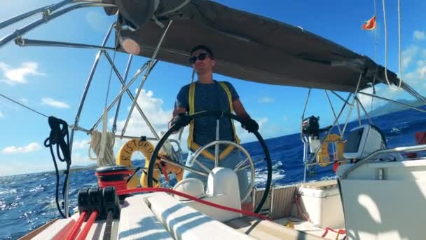 Knappe man hanteert een wiel van een drijvende boot — Stockvideo