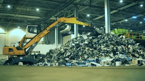Lixo, lixo, fábrica de reciclagem de resíduos. Escavadeira está trabalhando no ferro-velho dentro de casa — Vídeo de Stock
