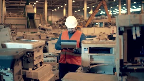 Trabajador de desguace está inspeccionando máquinas de oficina desechadas — Vídeo de stock