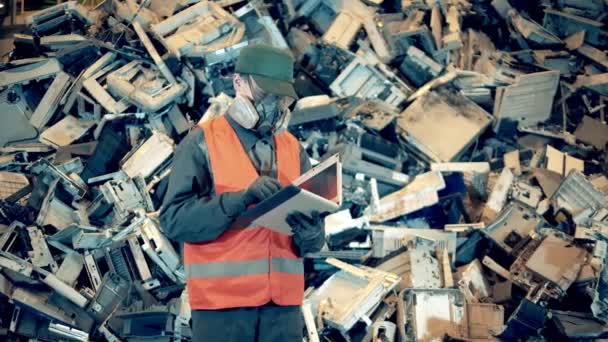 Trabajador del basurero está tomando notas al lado de una pila de basura — Vídeo de stock