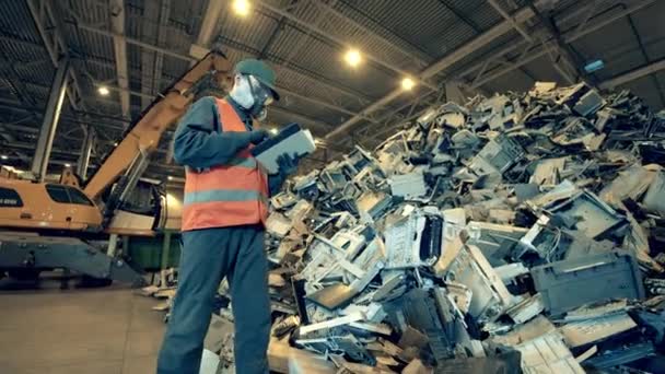 El empleado del basurero está observando una pila de dispositivos electrónicos rotos. Basura, basura, fábrica de reciclaje de residuos . — Vídeo de stock