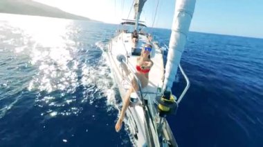 Two ladies onboard of a drifting boat are remote-filming themselves. Friends on a sailing boat during summer vacation, sea adventure.
