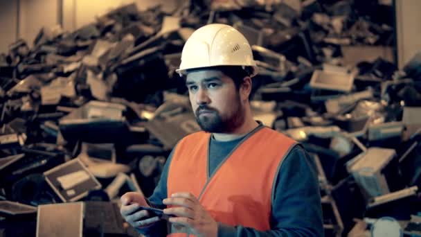 Male worker is operating a smartphone in the indoors junkyard — Stok video