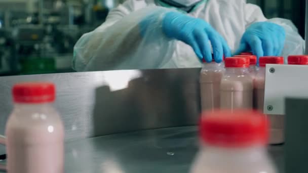 Yoghurt bottles are being displaced by a factory worker — Stock Video