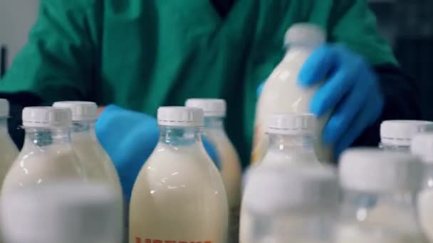 El trabajador de la planta está retirando las botellas de leche del transportador — Vídeo de stock