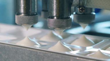 Makine konteynırları beyaz süt ürünleriyle dolduruyor.
