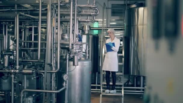 Леді-інспектор вивчає заводський блок з трубами — стокове відео