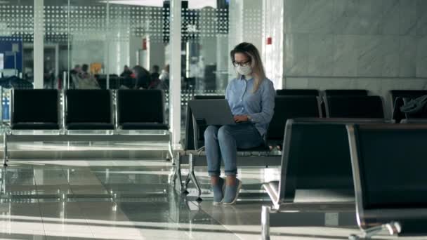 Salon de l'aéroport avec une dame portant un masque médical et utilisant un ordinateur portable — Video