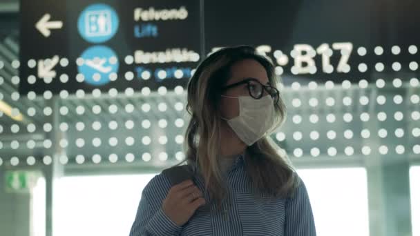 Senhora bonita em uma máscara de segurança está olhando ao redor no aeroporto — Vídeo de Stock