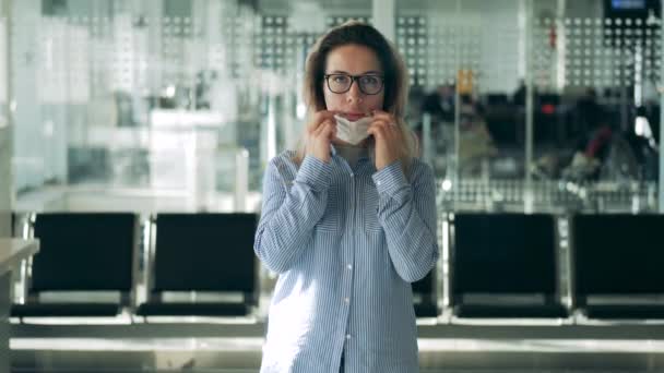 Schöne Frau mit Brille setzt sich eine medizinische Maske auf — Stockvideo