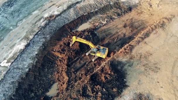 Excavadora amarilla moviendo tierra mientras trabajaba en una cantera. Maquinaria pesada en obra industrial . — Vídeo de stock