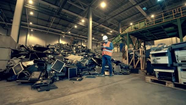 Recycling industry, used electronic recycling factory. Landfill worker with a smartphone near a pile of debris — Stock Video