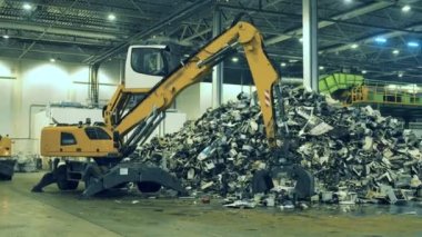Mekanik yükleyici çöpü alıp yığının içine koyuyor. Çöp, plastik geri dönüşüm fabrikası.