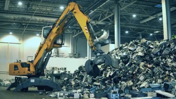 Graafmachine is het grijpen van stukken afval van een stapel. Recycling industrie, gebruikte elektronische recyclingfabriek. — Stockvideo