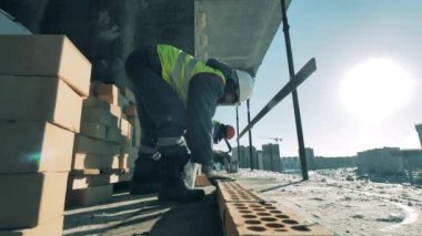 Erkek işçiler inşaat alanında betonla tuğla tamir ediyorlar.