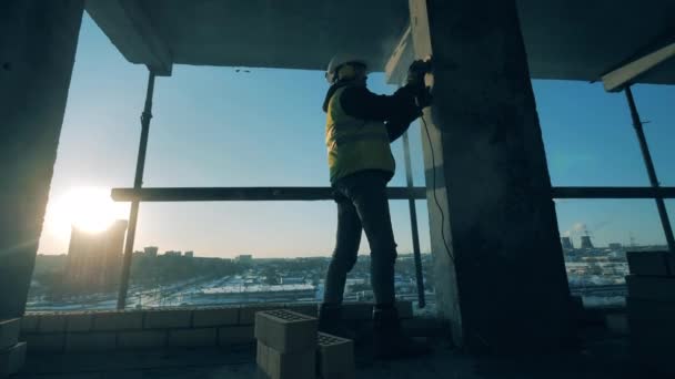 남자 건설자가 건축 현장에서 기둥을 연마하고 있다 — 비디오