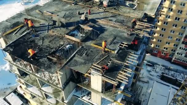 Un grupo de trabajadores en lo alto de un edificio en construcción — Vídeos de Stock