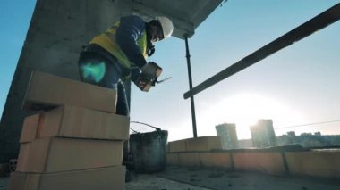 İnşaat işçisi tuğla ve çimento döşüyor.