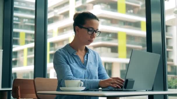 Cafe und eine Frau, die an einem Laptop arbeitet — Stockvideo