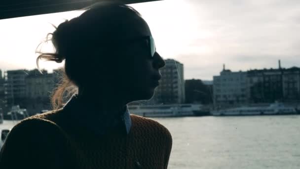 Femme en lunettes de soleil monte sur un bateau le long de la rivière de la ville — Video