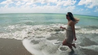 Muhteşem kadın deniz kenarında ağır çekimde koşuyor.