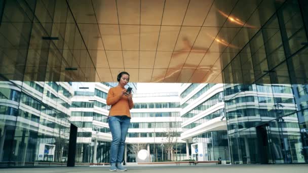 Una mujer está mirando su teléfono en una zona moderna de la ciudad — Vídeo de stock