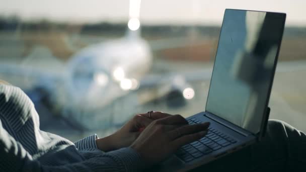 Ноутбук і жіночі руки друкують на ньому в аеропорту — стокове відео