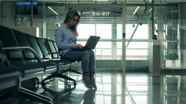 Empty departure lounge with a lady operating a laptop — Stock Video