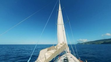 İçinde bir bayan olan yelkenli yeşil kıyıya doğru yüzüyor.