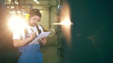 Verileri analiz eden bir erkek inşaatçı ile fabrika ünitesi basılıyor.