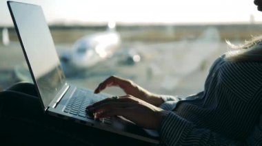 Laptop havaalanı penceresinin yanındaki bir kadın tarafından çalıştırılıyor.