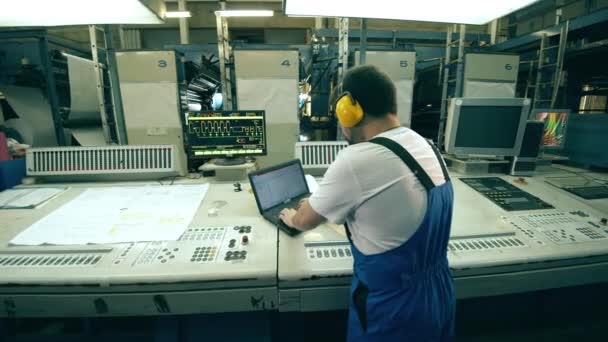 Vista trasera de un trabajador de tipografía que opera una placa de control — Vídeo de stock