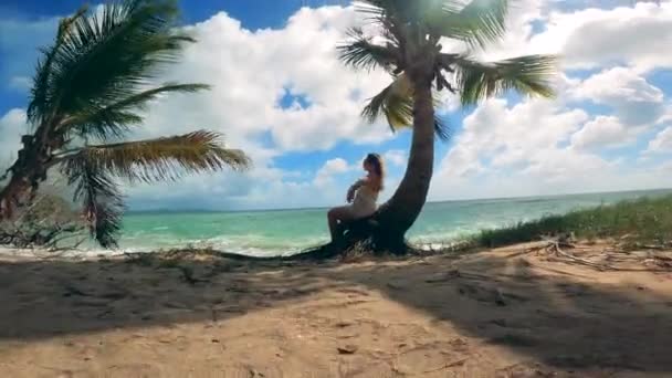 Une femme repose sur un palmier près de l'océan . — Video