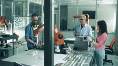 Genç bilim adamları bir robotik cihazı test ediyorlar. Yenilikçi laboratuvarda çalışan genç mühendisler..