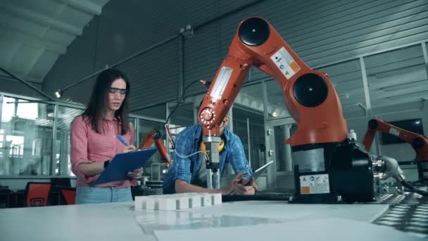 Estudiantes de ciencias están monitoreando un brazo robótico reubicando objetos — Vídeo de stock