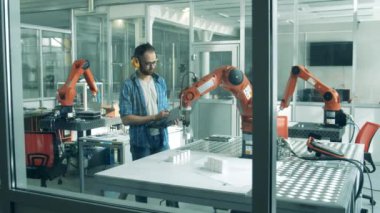 Fen öğrencisi bir laboratuarda robot aletini test ediyor.