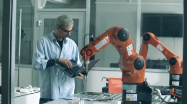 Bilim öğrencisi hareket halindeki bir robotik kolu izliyor.