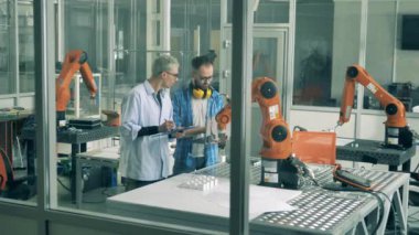 Genç araştırmacılar laboratuvarda bir robot cihazı test ediyorlar.